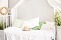 Provence, rustic style. Vase barrel with white daisy flowers in a bright, cozy bedroom interior. White wall, retro bed, straw hat.