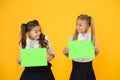 Providing information. Small children holding empty green papers for information on yellow background. Little girls