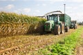 Combine harvester mowing corn on farm field and pouring into truck