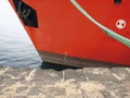 Prow front view of a large red merchant ship moored at the port quay. Rope tied to the hull of a bulk carrier ship moored in a Royalty Free Stock Photo