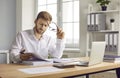 Prtrait of a young businessman looking through paper documents and working with laptop at office. Royalty Free Stock Photo