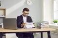 Prtrait of a young businessman looking through paper documents and working at office. Royalty Free Stock Photo