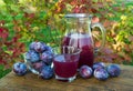 Prune juice in the carafe and glass with plums