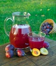 Prune juice in a glass and carafe with plums