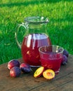 Prune juice in a glass and carafe with plums