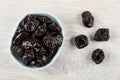 Prunes in blue bowl, dried plums on table. Top view