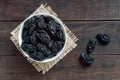 Prunes in a ceramic bowl on a dark wooden background.