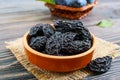 Prunes in a clay bowl and fresh plums, leaves on a wooden table. Royalty Free Stock Photo