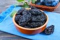 Prunes in a clay bowl and fresh plums, leaves on a wooden table Royalty Free Stock Photo