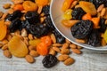 Prunes, dried apricots, dried mandarins and almonds in a bowl on a light wooden background Royalty Free Stock Photo