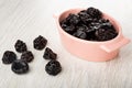 Prunes in pink bowl, dried plums on table