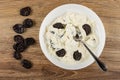 Prunes, plate with mix of cottage cheese, sour cream, dried plum, spoon on table. Top view