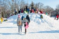 Pryluky, Chernihiv, Ukraine - 02/15/2021: Children ride with their parents on a snow slide in the city square