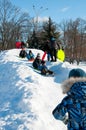 Pryluky, Chernihiv, Ukraine - 02/15/2021: Children ride with their parents on a snow slide in the city square