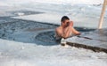 Pryluky, Chernihiv, Ukraine - 01 19 2021: Man dives in the cross-shaped hole in a frozen river and crosses itself