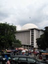 A corner of the istiqlal mosque there are many food vendors and crowded vehicles passing by