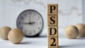 PSD2 - acronym on wooden cubes on graph, clock and wooden balls background