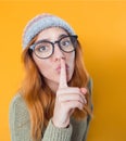 Psst. Young woman holding finger on lips,keep the secret concept, isolated on yellow background