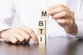 Psychological and personality test concept, Hand puts wooden cubes with MBTI, Myers-Briggs Type Indicator on table. Royalty Free Stock Photo