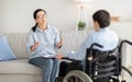 Psychotherapy for disabled teens. Young female psychologist speaking with teenage boy in wheelchair at office Royalty Free Stock Photo
