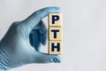 PTH is an acronym on cubes held by a hand in a blue glove