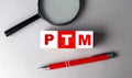 PTM word on wooden cubes with pen and magnifier Royalty Free Stock Photo