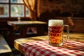 Pub interior, a mug of beer on top of a wooden table covered with red and white checkered tablecloth Royalty Free Stock Photo