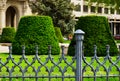 public city park in Budapest with decorative old gray cast iron railing. low picket fence. lush green lawn