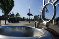 Public drinking fountain on street with cars and green treen at