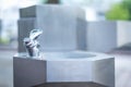 Public drinking water, stainless steel faucet with water droplets, outdoor green garden background