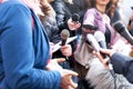 Public figure talking to the media, journalists holding microphones at news conference