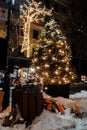 Public Garbage and waste cans overflown with drinks with plastics lids and snow close to Christmas lights and decorations