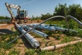 Public lighting poles lying on the ground next to the excavator on the construction site.