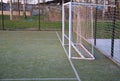 Public multifunctional city playground with green artificial turf. soccer goals. protective white nets and game lines. around are