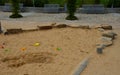 Public multifunctional playground with a sandy impact zone and a stainless steel slide in the park with a sandpit, a and a rope la Royalty Free Stock Photo