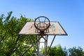 Public outdoor basketball court hoop, with trees in the background, and a sunny blue sky