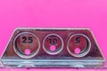 Public phone coin slots on pink background wall