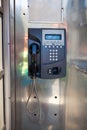 Public phone in steel booth with physical land line communication, push button phone Royalty Free Stock Photo