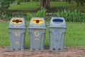 Public recycle bins or segregated waste bins located on concrete floor beside walkway in public park.