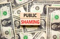 Public shaming symbol. Concept words Public shaming on wooden blocks on a beautiful background from dollar bills. Business and