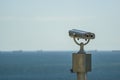 Public stationary binoculars on the seashore, metal binoculars on blurred sea background