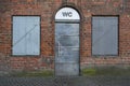 Public toilet with a gray metal door and a sign WC in a historic red brick building in the old town city center of Lubeck, Germany