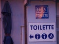 Public toilet and signs on it. A sign with information about a public toilet. WC