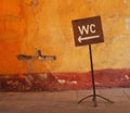 Public toilet WC, water closet wooden sign, old and bent.