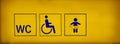 Public toilets signs with a handicapped accessible symbol and baby changing room on yellow neon sign