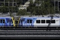 Two yellow-blue metro trains run side by side on the many tracks in Melbourne, Australia
