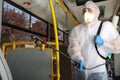 Public transport sanitation. Worker in suit disinfecting bus salon, focus on spray machine nozzle