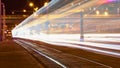 Public transportation in a city. Tram leaving the station, traffic lights, people, street, houses, overhead wires, rails. Movement