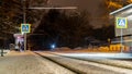 Public transportation in a city. Tram leaving the station, traffic lights, people, street, houses, overhead wires, rails. Movement