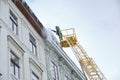 Public utilities on special vehicles remove icicles from the roofs of houses on the Rynok square in Lviv. Roof Winter Workers